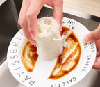 Hand using a natural loofah sponge to scrub sauce off a white plate.