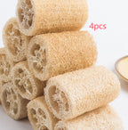 Four natural loofah sponges arranged in a pyramid stack on wooden background.
