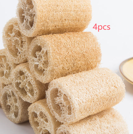 Four natural loofah sponges arranged in a pyramid stack on wooden background.