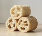 Three natural loofah sponges stacked together on a wooden background.