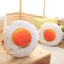 Two realistic fried egg pillow plush toys displayed in cozy home scene, soft funny food shaped stuffed throw cushion for living room decor