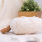 Side profile laying pose boiled egg plush toy, showcase thick fluffy plush fabric texture, cozy home lifestyle shot for food shaped stuffed toy