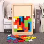 Colorful wooden tetris puzzle board with scattered geometric pieces on a carpet next to books.